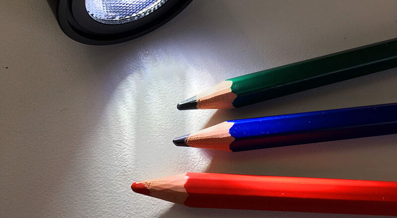 Verschiedenfarbige Buntstifte mit Taschenlampe angestrahlt
